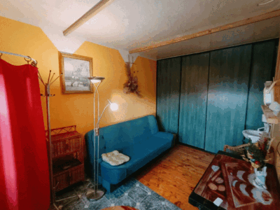 Pokój z żółtymi ścianami, niebieską kanapą, drewnianymi meblami i czerwoną zasłoną.