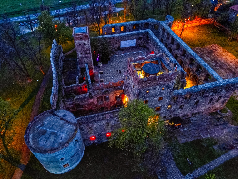 Zamek w Ząbkowicach Śląskich nocą z lotu ptaka, oświetlony w środku.