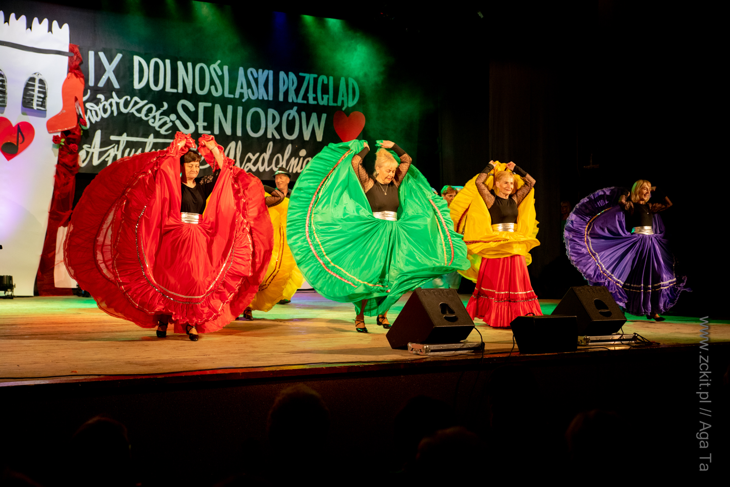 Scena Ząbkowickiego Centrum Kultury i Turystyki. Znajdują się na niej kobiety tańczące w szerokich kolorowych spódnicach.